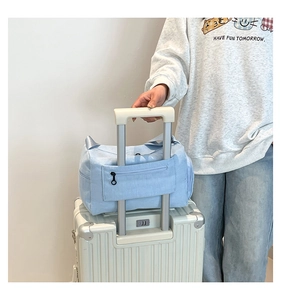 Detail view of sky blue travel bag with back sleeve for suitcase handles