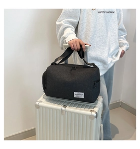 Detail of black canvas tote bag on white suitcase showing large capacity and handles