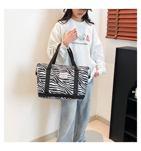 Detail of zebra print canvas tote featuring dual handles and a wet-dry separation pocket