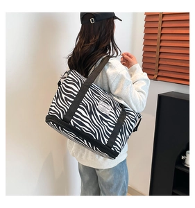 Detail of zebra print canvas bag featuring a double zipper shoe compartment and woven label