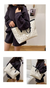 Detail of white textured tote bag featuring black bow embroidery and slim straps