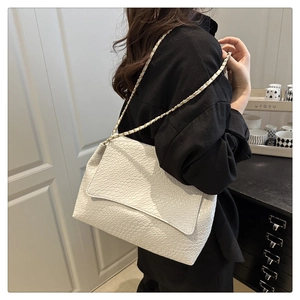 Detailed view of the white woven texture and elegant gold chain strap on the shoulder bag