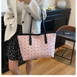 Detail of pink bow-print tote bag with pleated texture and black leather straps
