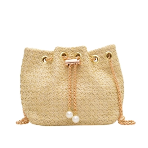 Fashionable straw bucket bag with gold chain strap and pearl drawstring details