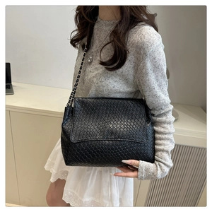 Détail d'un sac à bandoulière tissé noir avec chaîne et finition texturée premium