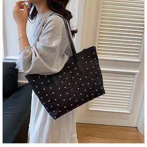 Détail du sac cabas plissé noir avec broderie nœuds blancs et bandoulière longue