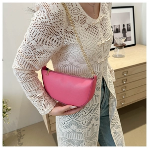 Rosafarbene Halbmond-Tasche mit Litschistruktur und goldener Kette in eleganter Umgebung