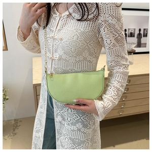 Close-up of light green pebble leather crescent bag with elegant gold chain strap