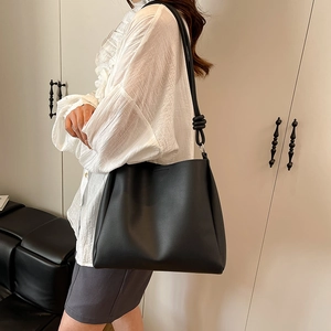 Sac seau minimaliste en cuir noir avec bandoulière à nœuds unique pour le quotidien