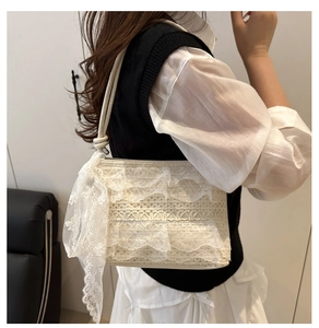 Dettaglio della borsa a tracolla in pizzo bianco con nastri e texture del tessuto
