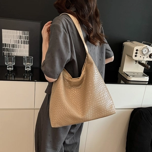 Large khaki woven tote bag for women showing a stylish over the shoulder look on a model