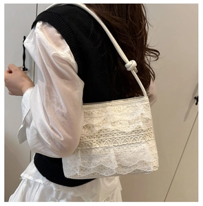 Dettaglio della borsa hobo in pizzo bianco con balze a strati e manico a nodo elegante