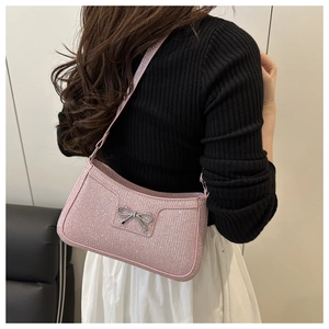 Detail of pink sequin shoulder bag featuring a decorative silver metal bow accent