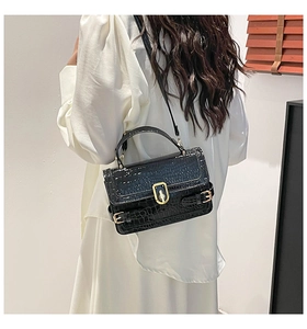 Detail of black crocodile texture handbag with gold buckle and stylish shoulder strap