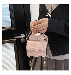 Détail du sac rose avec rabat ondulé, bandoulière chaîne dorée et grand nœud décoratif