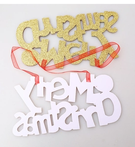 Detail of glittery Happy New Year and Merry Christmas hanging signs with red ribbons