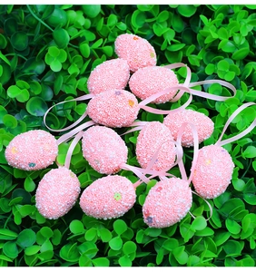 Uova di Pasqua rosa maculate con adesivi floreali su decorazione di erba sintetica