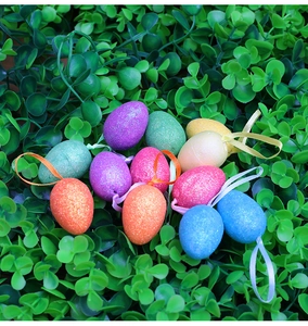 Dettaglio di uova di Pasqua colorate con brillantini e nastri su sfondo di foglie verdi