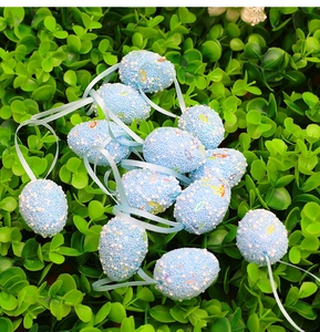 Dettaglio di uova di Pasqua blu chiaro con perline di schiuma e paillettes su foglie verdi