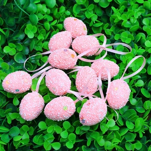Ornamenti colorati per uova di Pasqua con perle bianche e nastri rosa su prato verde
