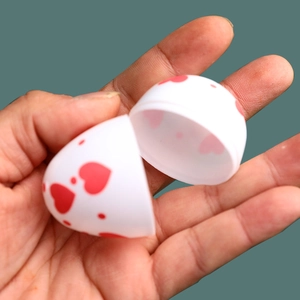 Uovo di Pasqua in plastica colorata con cuori rossi mostrato aperto in mano