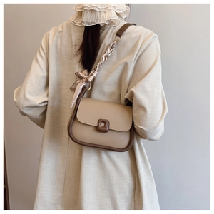 Detail of crossbody bag with silk scarf strap and elegant contrast piping finish