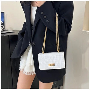 Detail of white crocodile texture crossbody bag with gold lock on black blazer outfit