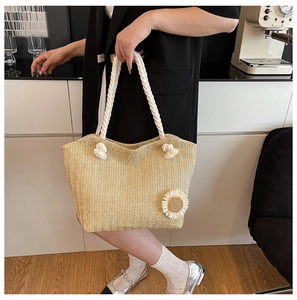 Detail of straw bucket bag with white thick rope handles and knit sunflower ornament