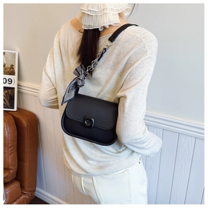 Détail du petit sac noir avec bandoulière chaîne enroulée d'un foulard et fermoir rotatif