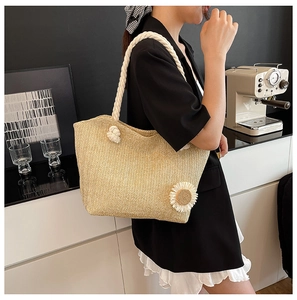 Detail of hand-woven straw tote with thick white rope handles and decorative fabric flower