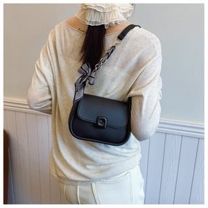 Crossbody black matte square bag with silk scarf detail shown on person from behind