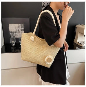 Detail of hand-woven straw bucket bag with floral accent and thick cotton rope handle