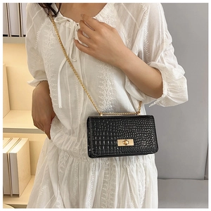 Detail of black crocodile texture bag with gold chain strap and metallic clasp