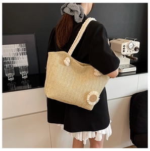 Detail of hand-woven straw bucket bag featuring a white sunflower and rope handle