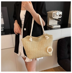 Detail of straw bucket bag with white rope handle and 3D daisy flower accent
