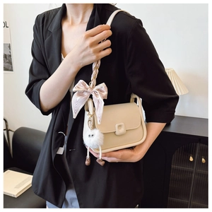 Chic cream leather crossbody bag with silk scarf strap and plush monster pendant
