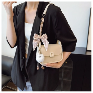 Detail of cream saddle bag with striped silk scarf and cute white plush doll charm