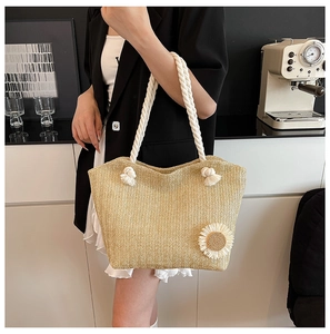 Detail of beige woven straw tote with sunflower accent and white rope shoulder strap