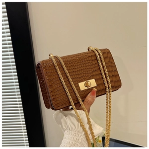 Detail of brown crocodile pattern small square bag with golden chain and metal lock
