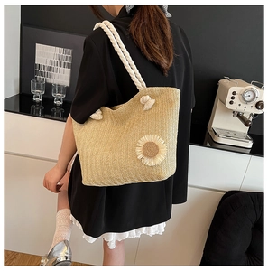 Detail of hand-woven straw tote with sunflower design and cotton rope straps for summer