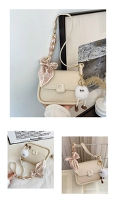 Detail of cream shoulder bag featuring decorative silk scarf handle and plush doll charm