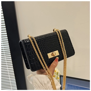 Detail of black crocodile embossed shoulder bag with gold chain strap and twist lock clasp