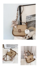 Detail of khaki saddle bag with striped silk scarf and cute plush pendant decoration