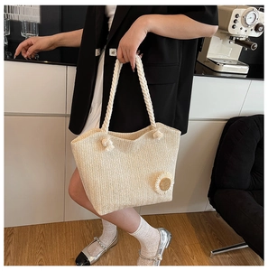 Detail of hand-woven beige tote bag featuring a textured weave and a 3D daisy flower charm