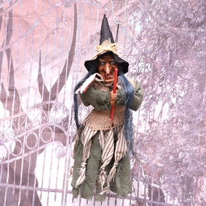 Hanging Halloween witch decoration with green robe, black hat and a red broomstick prop