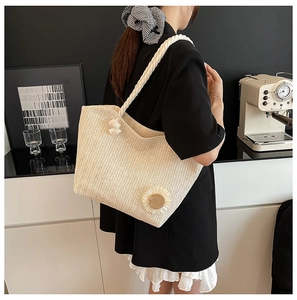 Detail of straw bucket bag featuring a woven sunflower and thick cotton rope handle