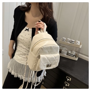 Close-up of white quilted mini backpack featuring metal turn-lock and leather chain strap