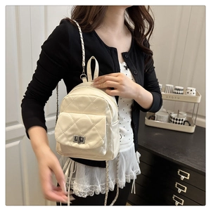 Detail of cream quilted backpack featuring silver twist lock and chain strap on model