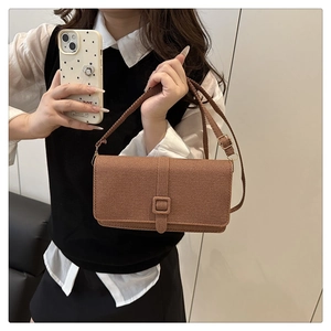 Detail of a brown woven texture crossbody bag with a square buckle on the flap