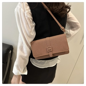 Detail of dark brown textured crossbody bag with gold hardware and adjustable strap